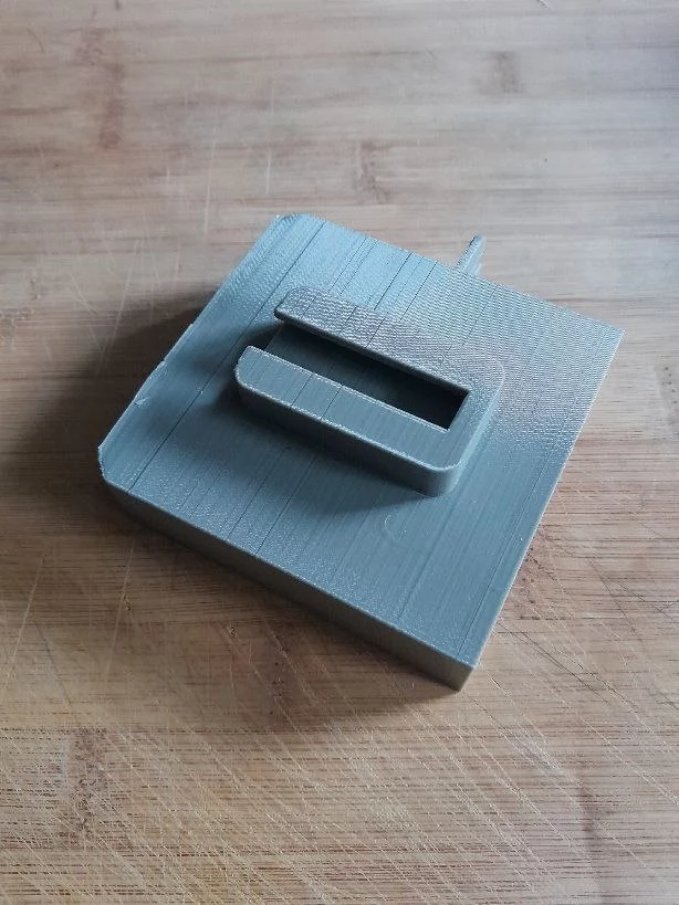 la face arrière du support pour téléphone, avec un connecteur qui va s'emboîter sur les deux moitiés de la pince