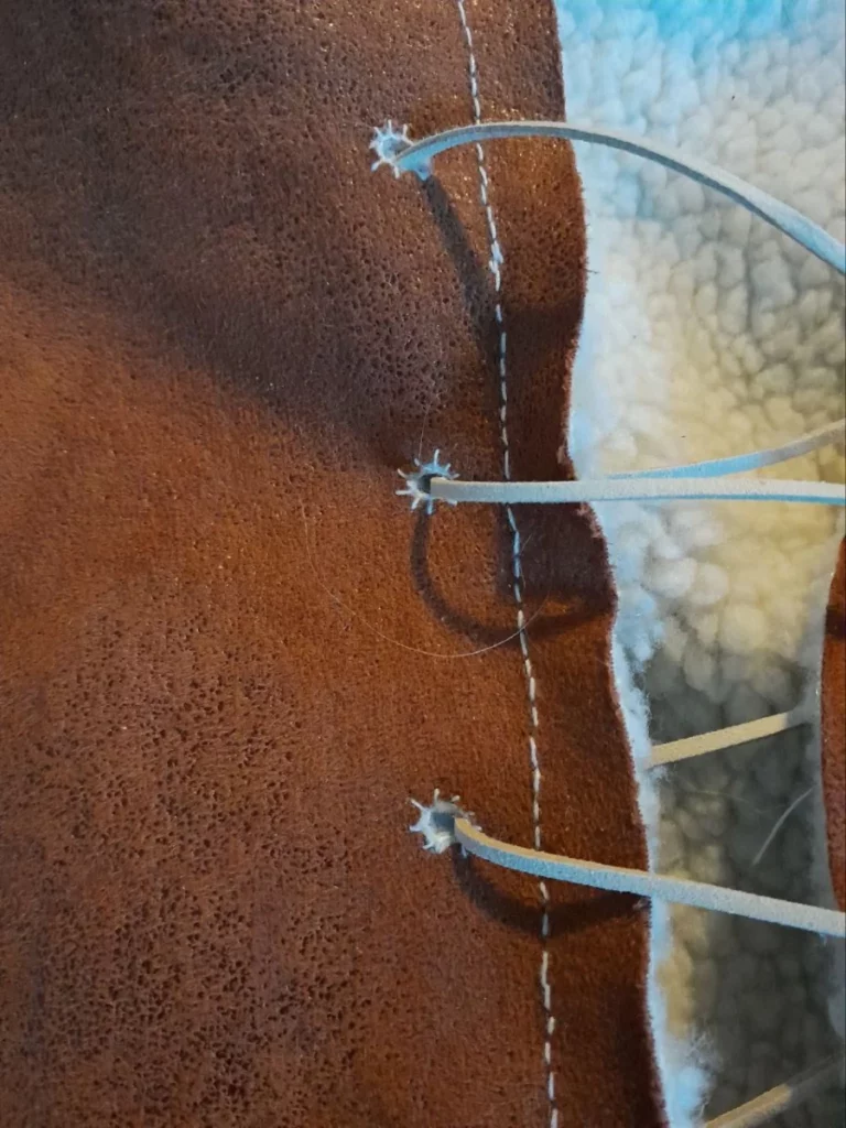 Détail de trois oeillets assez simples et irréguliers cousus main en fil de coton blanc