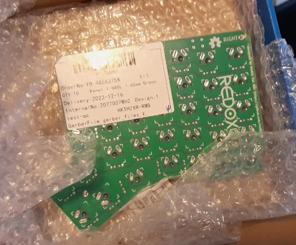 une pile de PCB vertes pour des claviers "split", emballées dans du papier à bulles