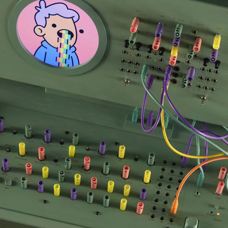 military green modular synth with multicolor connectors and a round screen with a blonde boy puking rainbow liquid