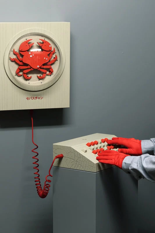 a synth contraption where the keyboard controls the legs of a crab on a frame on a wall