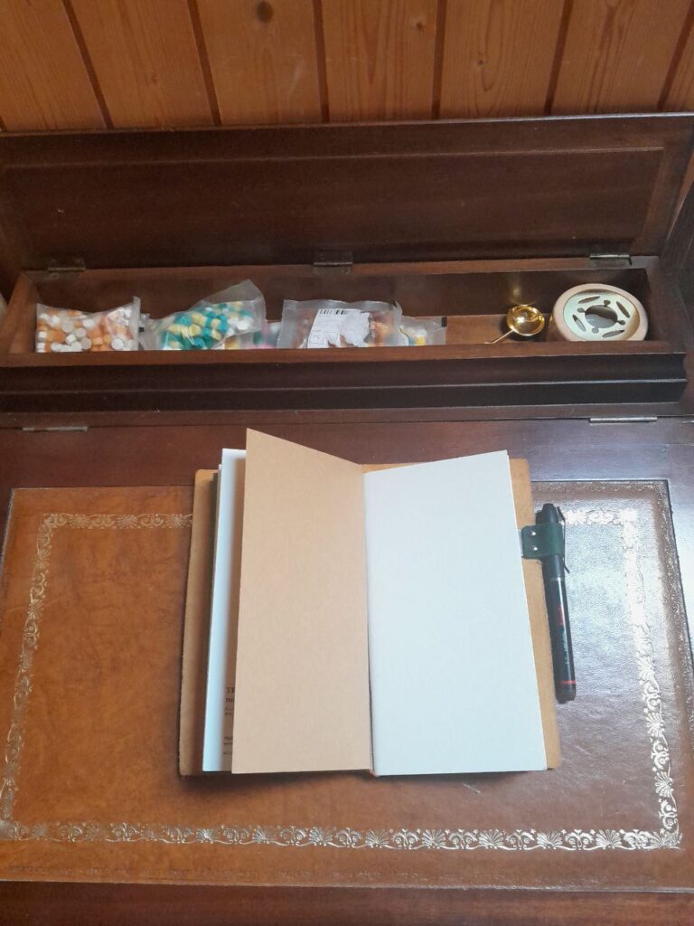 vue du rangement supérieur à charnières - probablement desiné à l'encrier et à la plume - actuellement plein de petits pellets de cire à cacheter multicolore