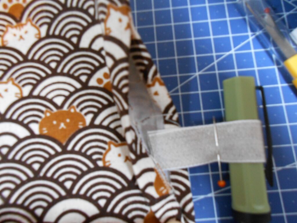 gros plan sur un capuchon de stylo enroulé par un morceau de ruban gros grain, lui-même inséré dans une ouverture entre deux pièces de tissu