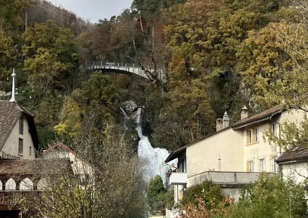 au pied du Jura, très à pic, il y a un restaurant dans un bâtiment rustique et traditionnel, juste à côté d'une cascade qui se déverse entre deux pics, sous un pont