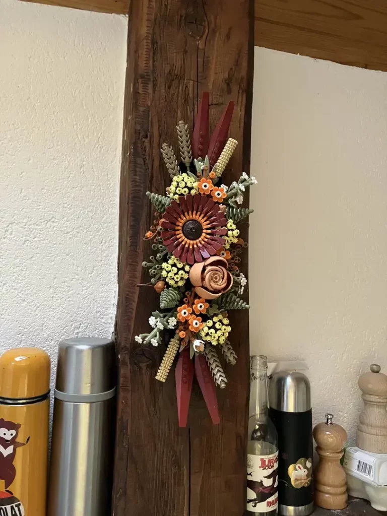 Gros plan sur cette même composition florale accrochée à la poutre, entre un set de thermos colorées et décorées